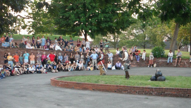 The audience gathers at various settings on Governor's Island, many commenting that they have never explored the island's fields and cul-de-sacs.